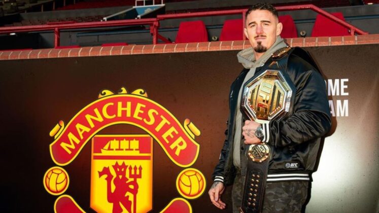 Tom Aspinall holding his UFC belt in Manchester United stadium